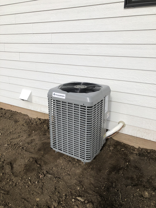 A new Champion outdoor AC unit installed next to a residential home by Air Care, an HVAC contractor in Sioux Falls, SD.