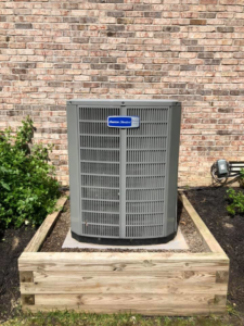 A newly installed American Standard outdoor AC unit next to a brick home by Fellowship Heating and Cooling in Indianapolis, IN.