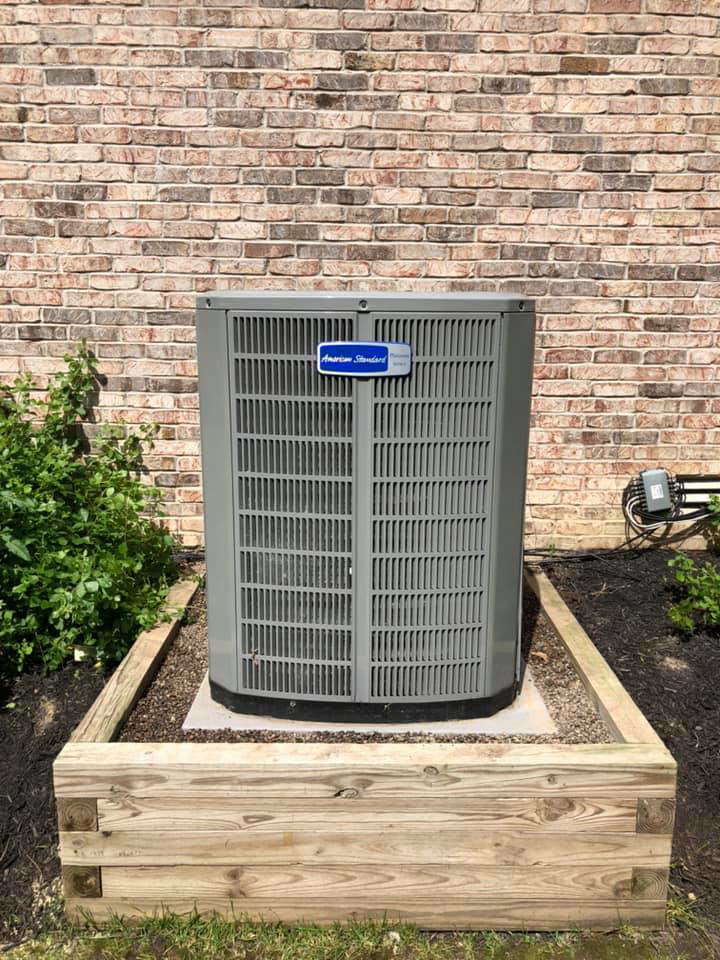 A newly installed American Standard outdoor AC unit next to a brick home by Fellowship Heating and Cooling in Indianapolis, IN.