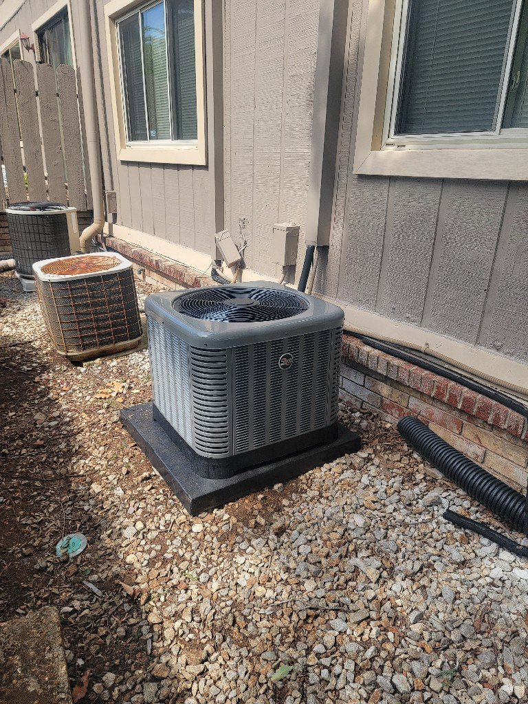 A new HVAC condenser unit installed next to an older unit by Integrity Services Heating and Cooling in Madison, AL.