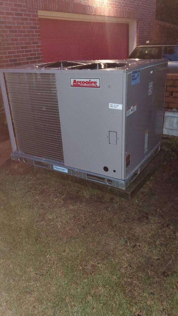 A newly installed Arcoraire outdoor HVAC unit next to a brick garage by West Tennessee Heat & Air in Memphis, TN