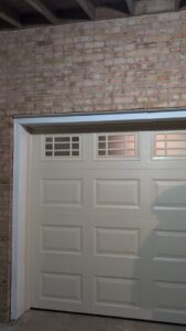 A newly installed beige garage door with windows by Gilliam Services LLC in Johnson City, TN.