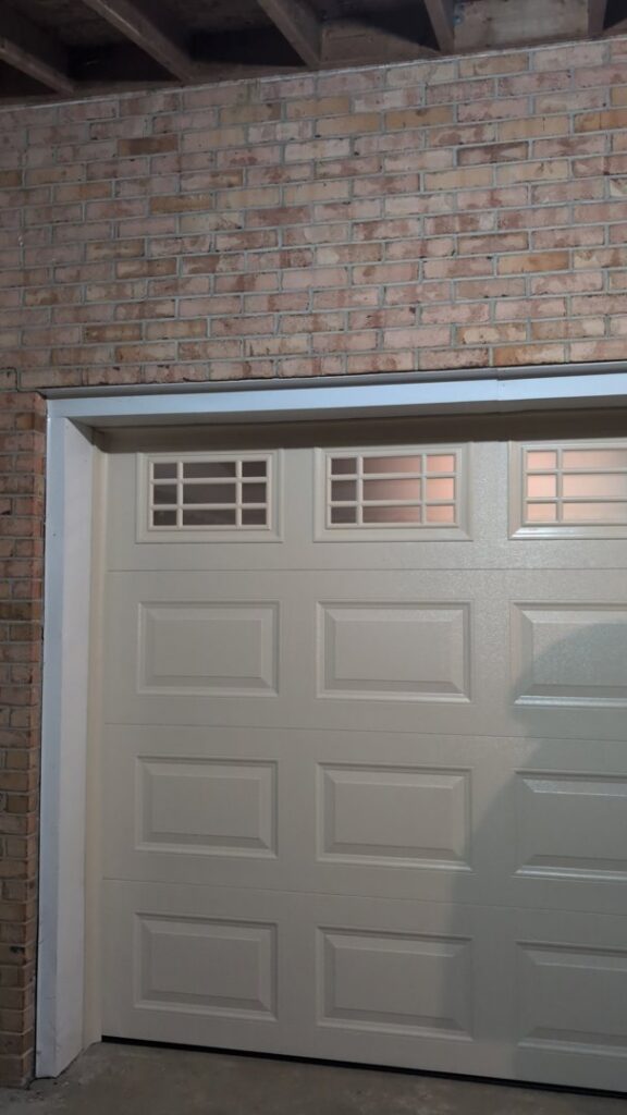 A newly installed beige garage door with windows by Gilliam Services LLC in Johnson City, TN.