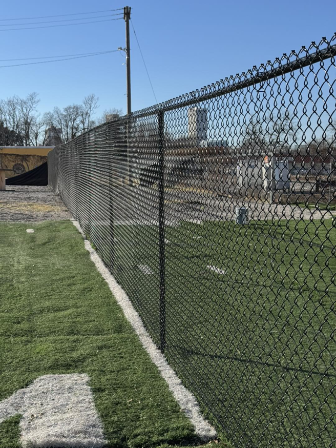 A newly installed black chain-link fence bordering an artificial turf field by Just Handy Fence and Stain LLC in Tulsa, OK.