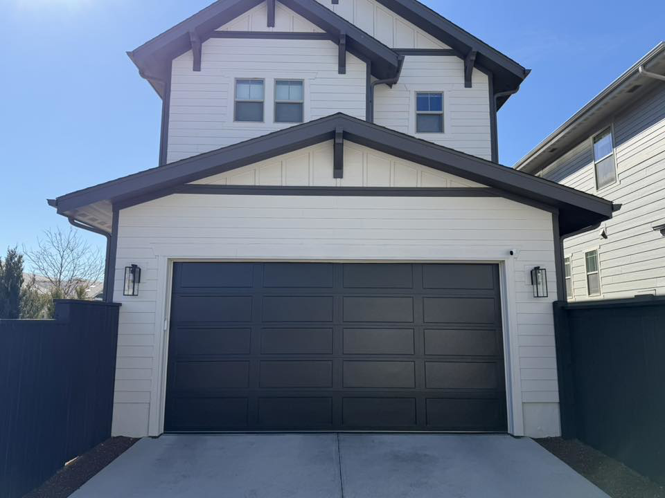 A newly installed modern black garage door on a white house by 365GarageDoor in Dallas, TX