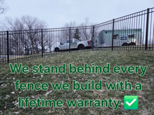 A newly installed black metal fence on a hill by Green Acres Fence Co in Salina, KS, with their truck and trailer visible.