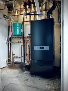 A newly installed black boiler and water heater system with copper piping by HVAC Fellows in Boston, MA.