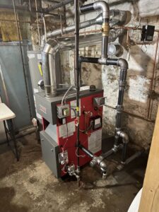 A newly installed red boiler and piping in a utility room by Air Done Right in Philadelphia, PA.