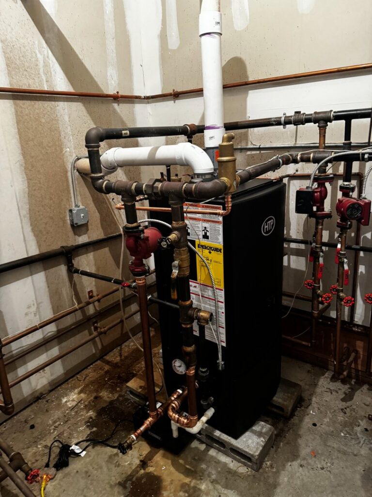A newly installed black boiler with copper piping and valves in a utility room by L&SON Heat AC Tech in Yonkers, NY.