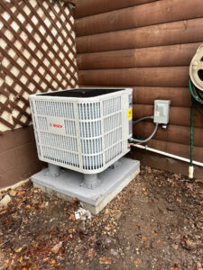A newly installed Bosch outdoor air conditioning unit on a concrete pad by One Hour Heating & Air Conditioning of Lancaster, PA.