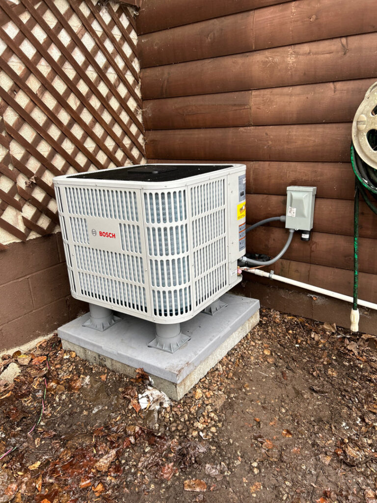 A newly installed Bosch outdoor air conditioning unit on a concrete pad by One Hour Heating & Air Conditioning of Lancaster, PA.