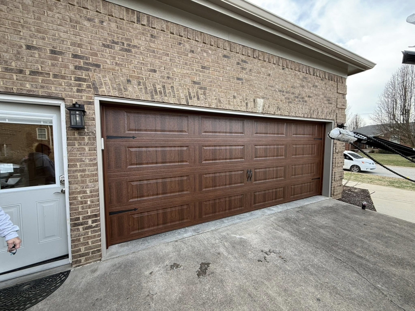 A newly installed brown garage door on a brick residential home by Guest Garage Door Company in Lexington, KY.