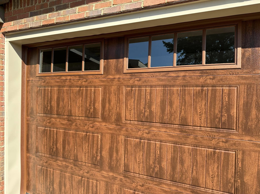 A close-up view of a new brown garage door with windows installed by Mike's Garage Door Repair in Wetumpka, AL.