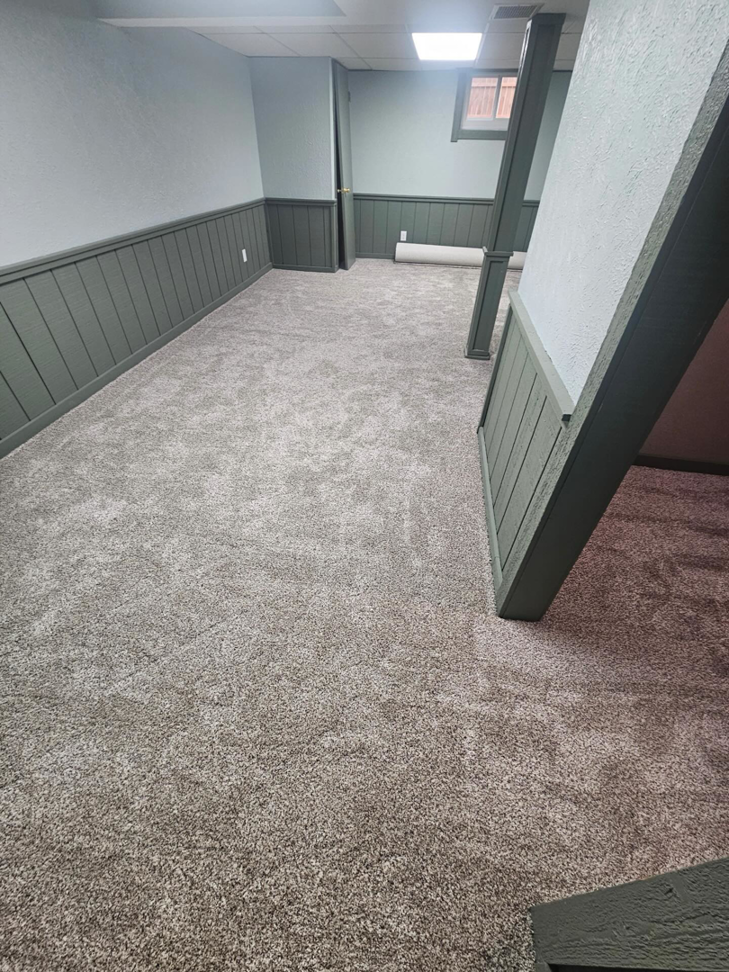 A room with new gray carpet installation and a carpet roll in the background by Carpets Mostly in Indianapolis, IN
