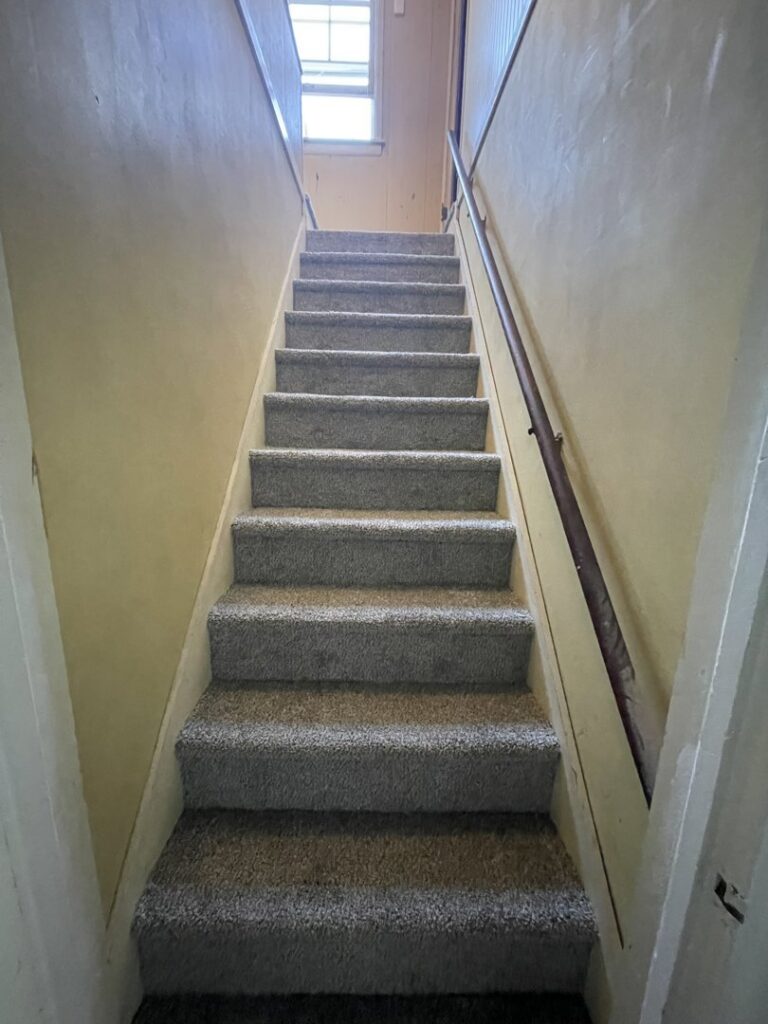 Newly installed gray carpet on a staircase by Flooring World Wide LLC in Plainwell, MI.