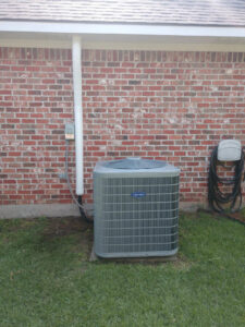 A newly installed Carrier air conditioning unit next to a residential brick house by ARKLA AIR LLC in Springhill, LA.