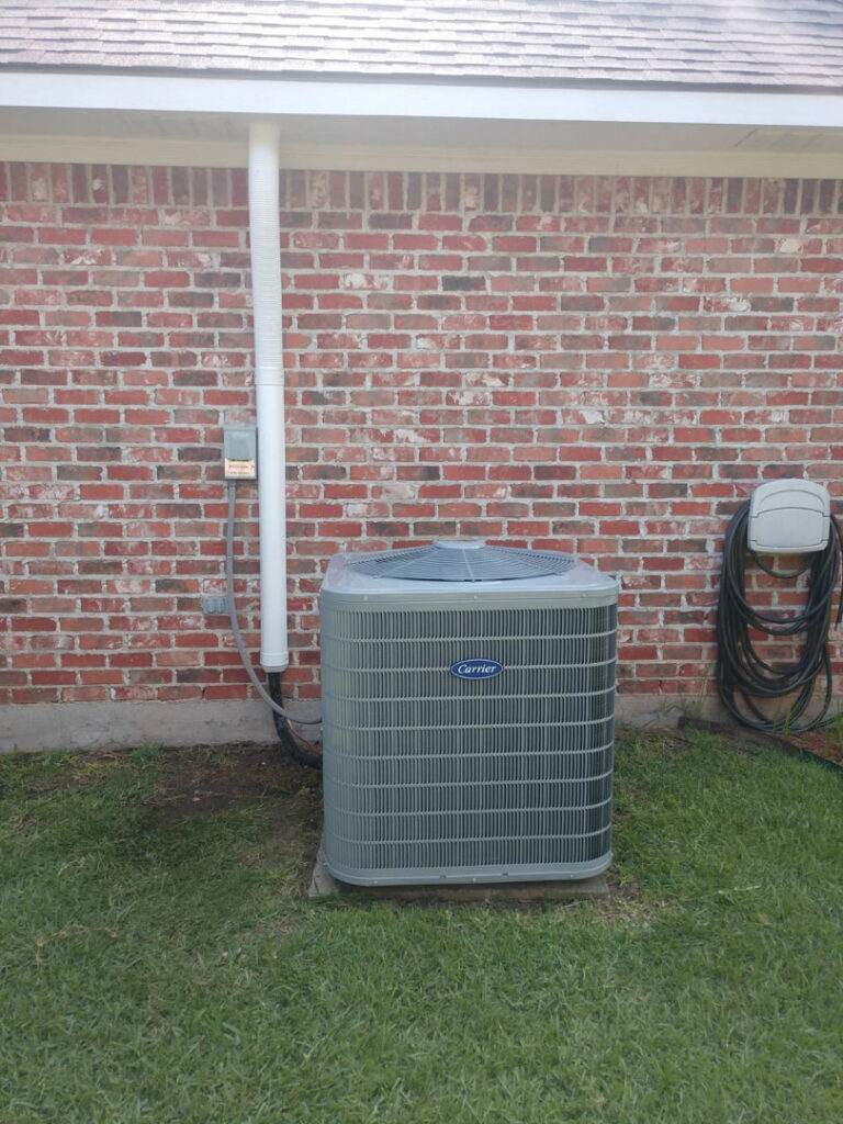 A newly installed Carrier air conditioning unit next to a residential brick house by ARKLA AIR LLC in Springhill, LA.