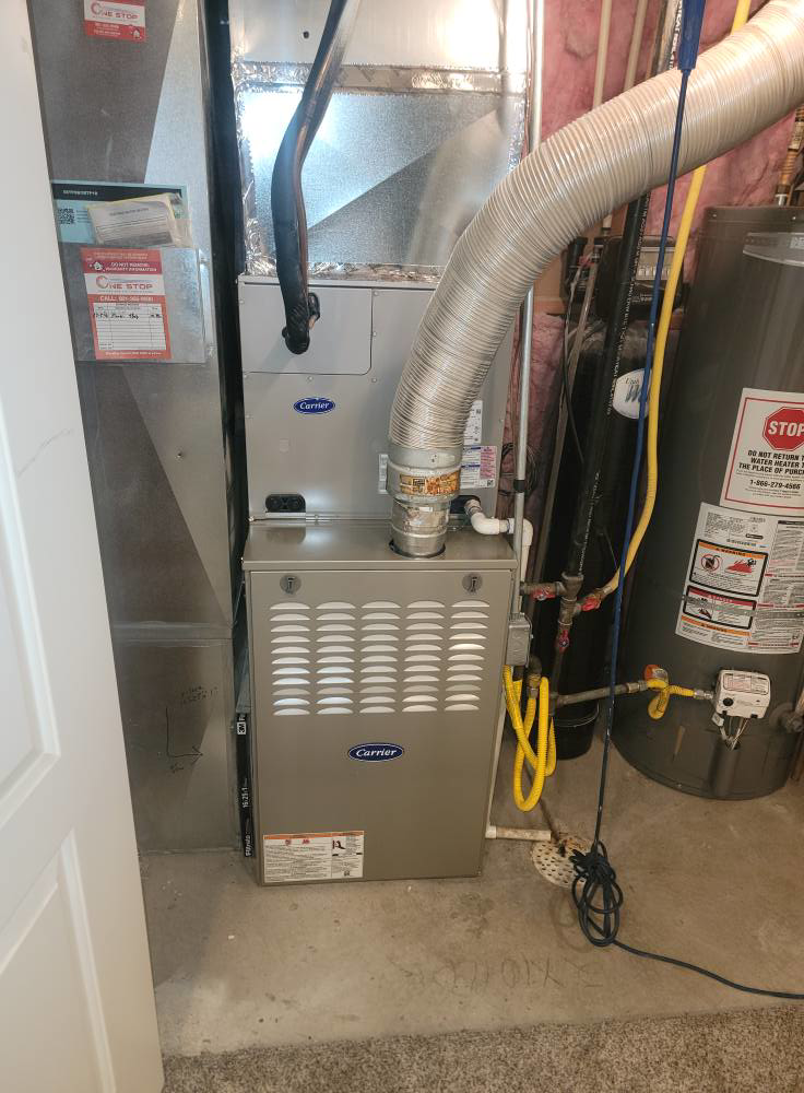 A newly installed Carrier HVAC furnace and water heater in a utility closet by Carter HVAC & Service in Seagrove, NC.