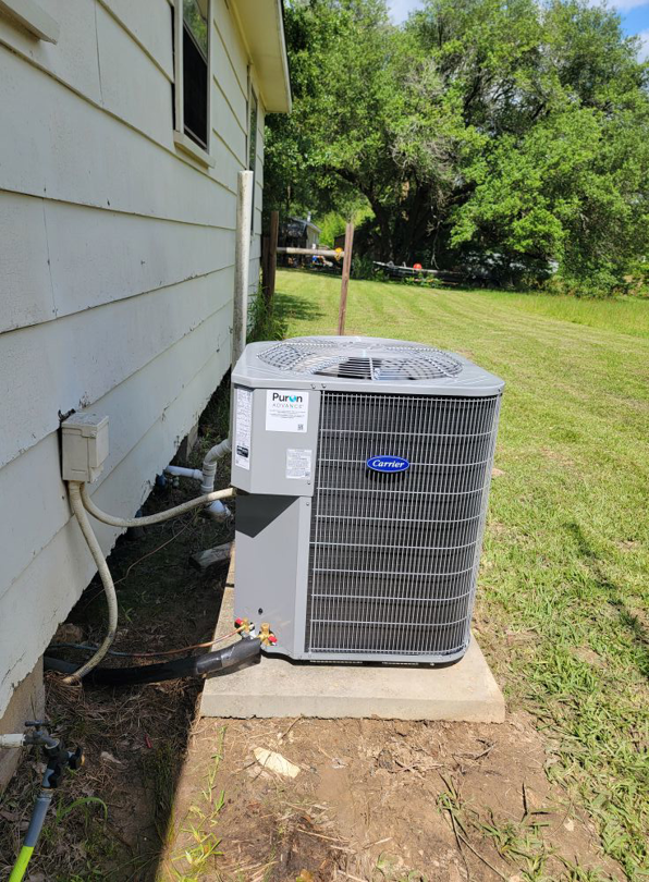 A new Carrier outdoor air conditioning unit installed next to a residential building by ARKLA AIR LLC in Springhill, LA.