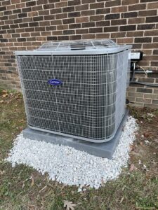 A newly installed Carrier outdoor AC unit next to a brick wall by Lee Air Conditioning in Lafayette, LA.