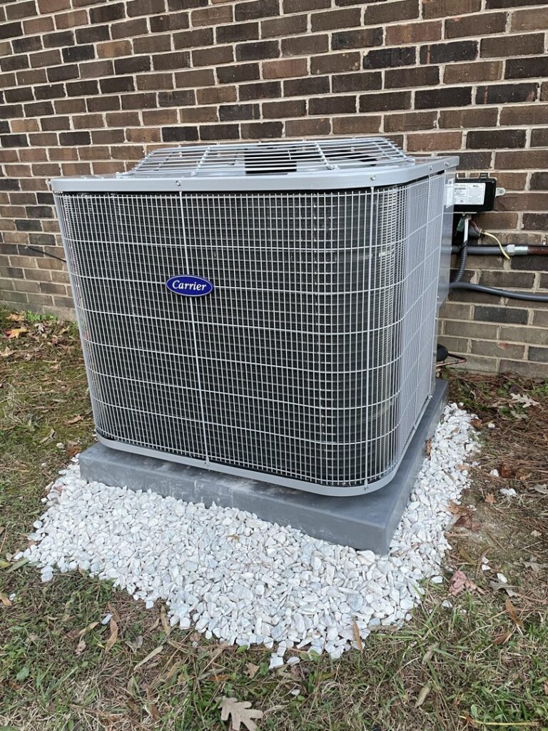 A newly installed Carrier outdoor AC unit next to a brick wall by Lee Air Conditioning in Lafayette, LA.