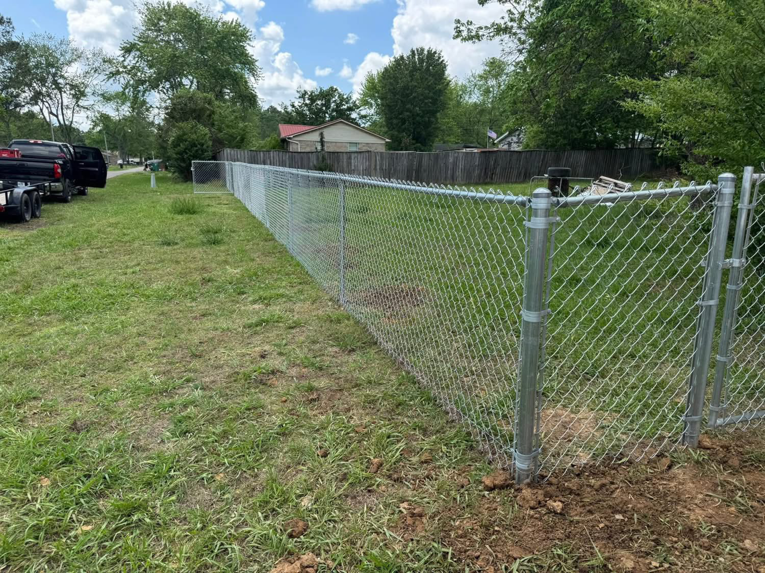 Newly installed chain-link fence with a gate in a residential yard by Faithful Fencing LLC in Batesville, AR.