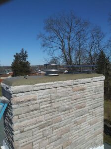 A newly installed chimney cap on a stone chimney by Centerville Pipestone Chimney Services LLC in Dayton, OH.