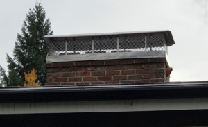 A newly installed metal chimney cap on a brick chimney by Matchbox Chimney Sweeps in Vancouver, WA.