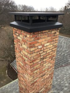 A newly installed black chimney cap on a brick chimney, showcasing a chimney service by HBR Hearth and Chimney in Dallas, TX