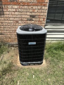 A new Comfortmaker AC unit installed on a concrete pad in a residential yard by Rhino Heating and Air Conditioning LLC in Norman, OK.