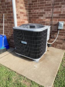 A newly installed Comfortmaker outdoor AC unit next to a brick wall, showcasing work by Rhino Heating and Air Conditioning LLC in Norman, OK.