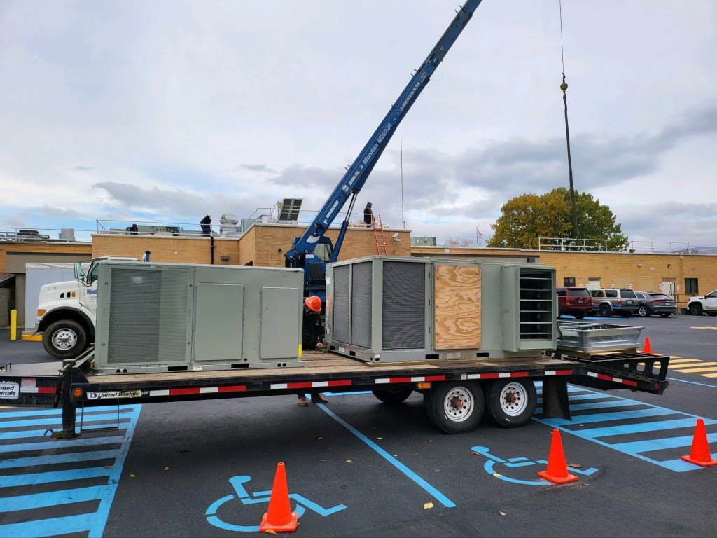 New commercial HVAC units on a trailer with a crane, ready for installation by AP HVAC in Ridgewood, NY.
