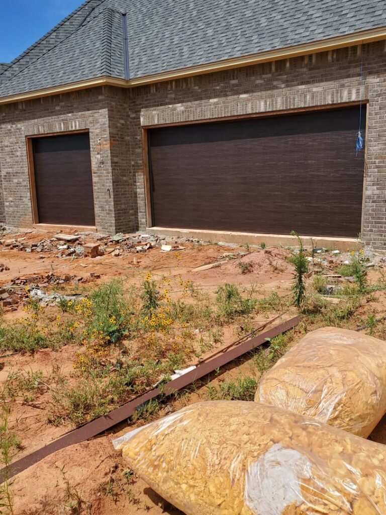 Two new dark brown garage doors installed on a brick house under construction by Garage Door Specialists Of Oklahoma Inc. in Midwest City, OK.