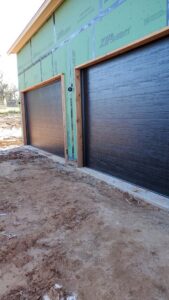 Two new dark brown garage doors installed on a house under construction by Garage Door Specialists Of Oklahoma Inc. in Midwest City, OK.