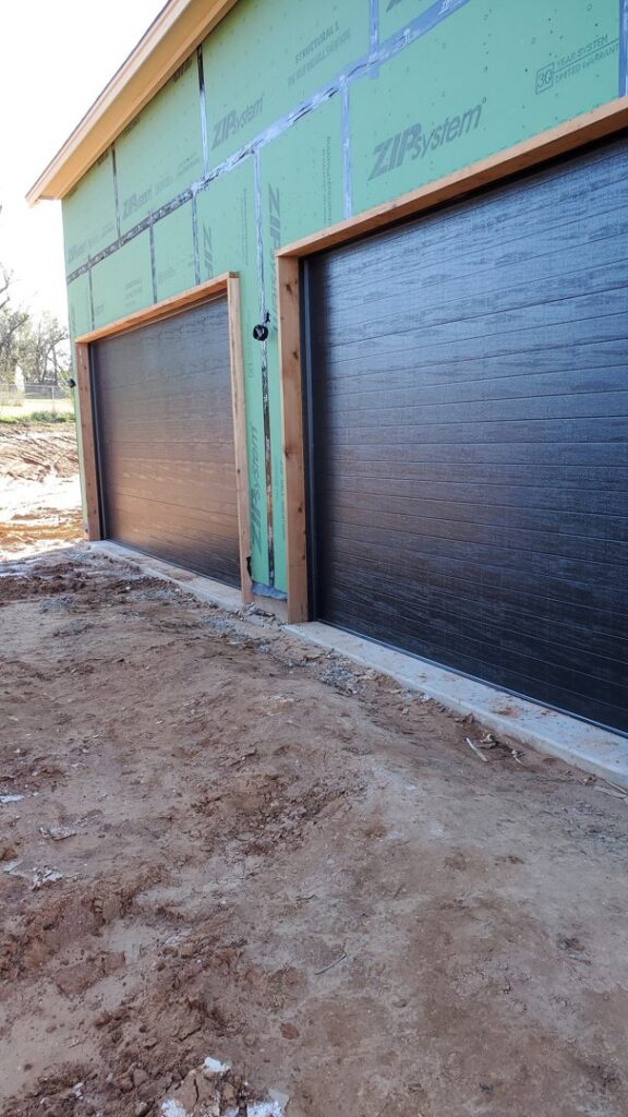 Two new dark brown garage doors installed on a house under construction by Garage Door Specialists Of Oklahoma Inc. in Midwest City, OK.