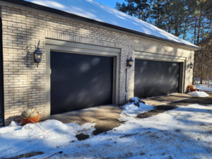 New dark grey garage doors installed on a brick house by LabraDoor Overhead Services in Eau Claire, WI.