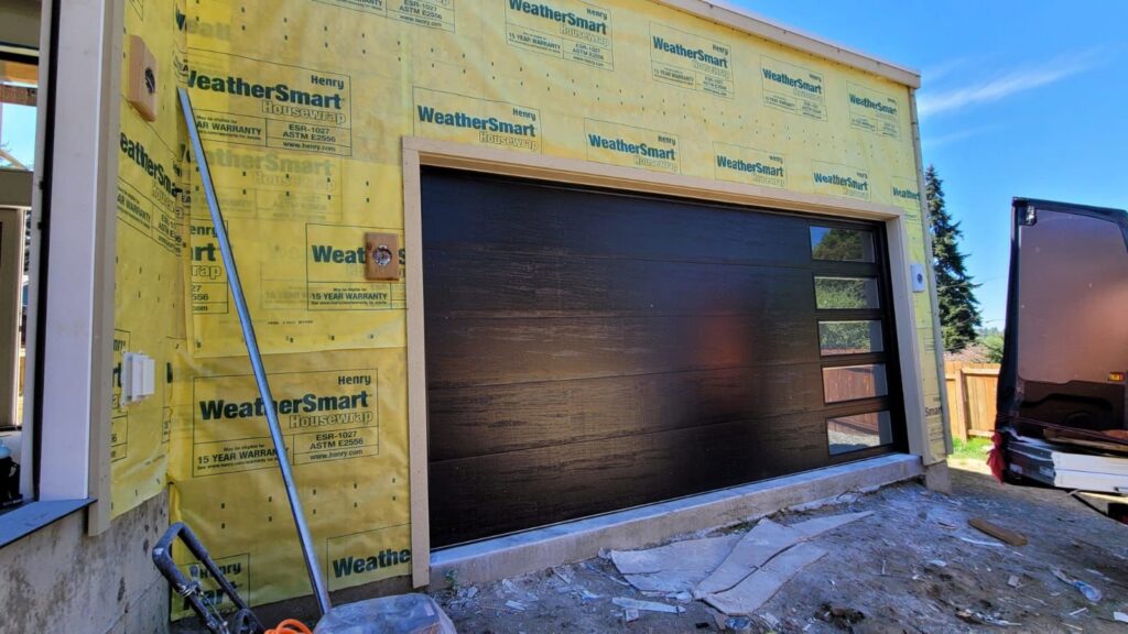 New dark wood-look garage door with frosted glass panels installed on a house by AAA Garage Door Services in Renton, WA