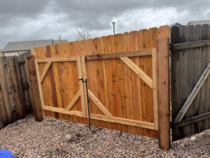 A newly installed double wooden gate with diagonal bracing in an existing fence by Slater Fence Co in Houston, TX.