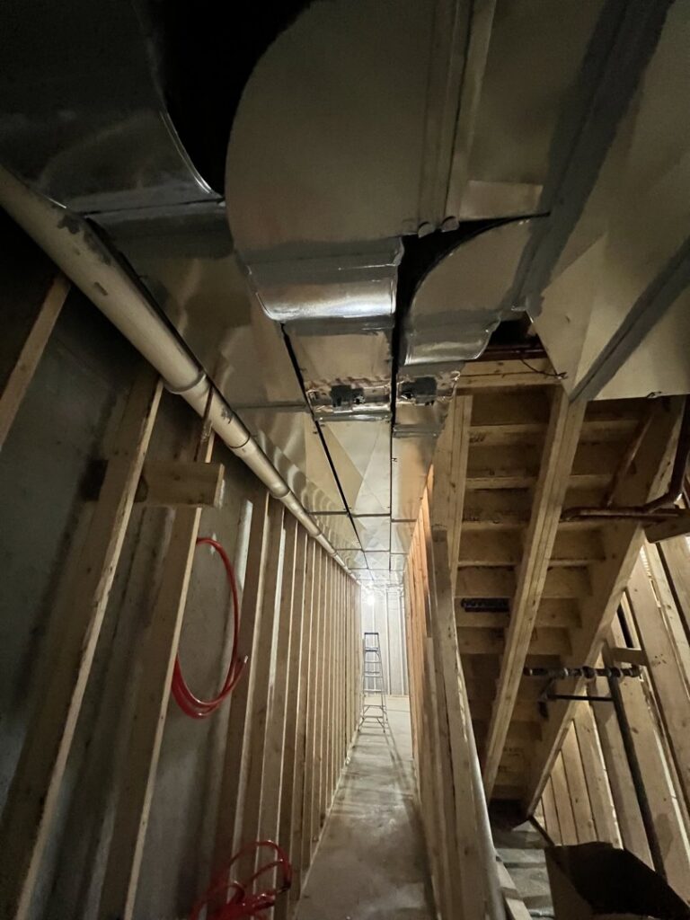 New ductwork being installed in a narrow utility space during construction by Adam's HVAC in Naperville, IL.