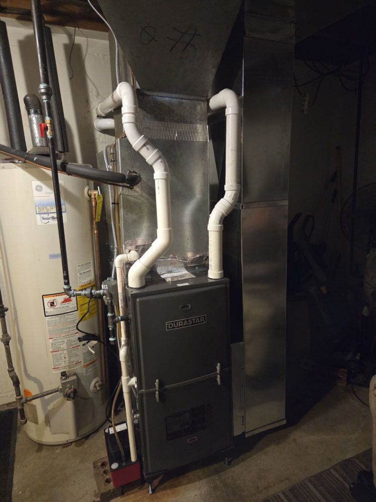 A new Durastar HVAC furnace unit installed with ductwork and a water heater in a basement by DWE Home Services in Cincinnati, OH.