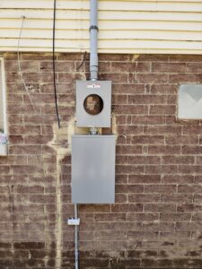 A new electrical meter and service panel installed on a brick exterior wall by Titus & Son's Electric in Bluffton, IN.