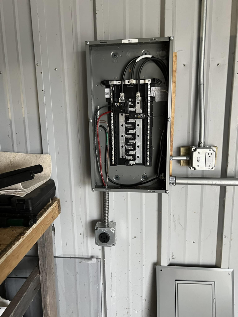 A newly installed electrical panel with conduits and wiring on a corrugated metal wall by F&C Electrical Services LLC in Iowa City, IA.