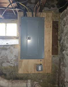 A newly installed electrical panel and outlet in a basement by Joey G Electric LLC in Waterbury, CT.