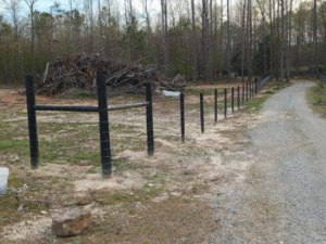 New fence posts and wire mesh installed along a gravel driveway by Almaraz & Sons LLC in Macon, GA.