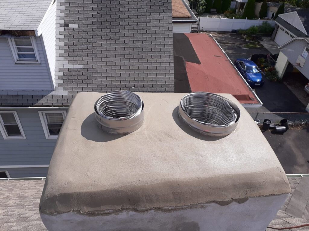 Two new flexible metal chimney liners installed at the top of a chimney, showcasing work by Colombus Chimney in Elizabeth, NJ.