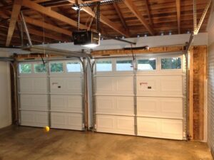 Interior view of a garage showcasing two newly installed white garage doors and automatic openers by IGD Garage Door Repair in Renton, WA.