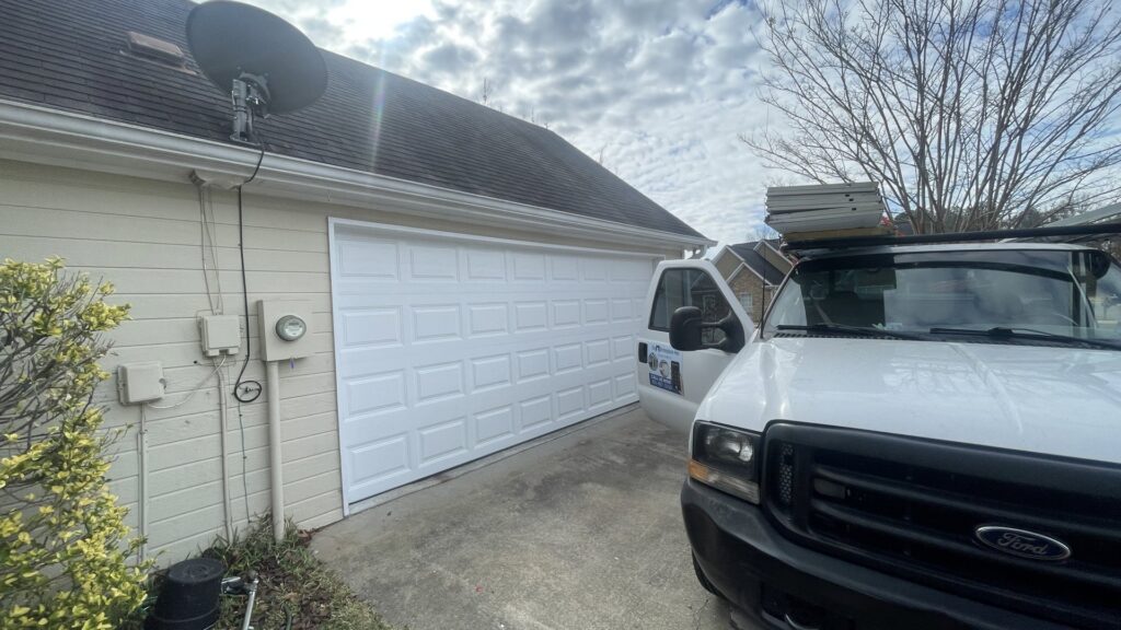 The Birmingham Man Garage Doors truck with new garage door panels on the roof rack, ready for installation in Birmingham, AL.