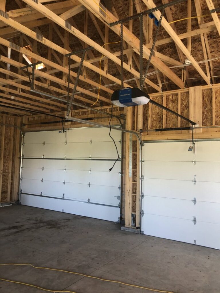Two new garage doors and openers installed in a garage under construction by Colorado Garage Door Guy in Aurora, CO.