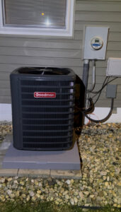 A new Goodman outdoor AC unit installed on a concrete pad with gravel landscaping by Buckeye Mechanical Construction in Columbus, OH.