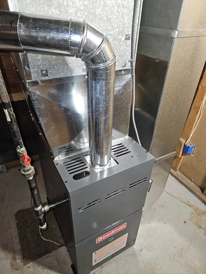 A newly installed Goodman furnace with connected ductwork and flue pipe by HVAC and Appliances repair LLC in Arlington, VA.